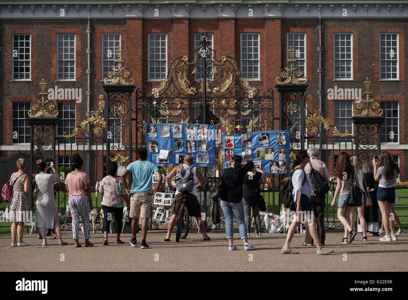 Leute schauen auf hommagen an das goldene Tor der Kensington Palace, London, im Vorfeld des 20. Jahrestages der Prinzessin Dianas Tod. Stockfoto