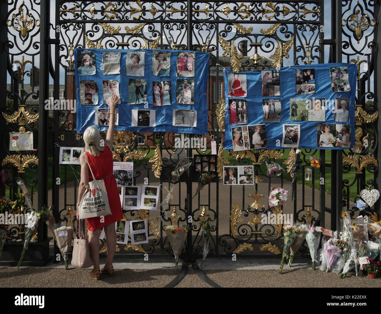 Eine Frau sieht Hommagen an das goldene Tor der Kensington Palace, London, im Vorfeld des 20. Jahrestages der Prinzessin Dianas Tod. Stockfoto