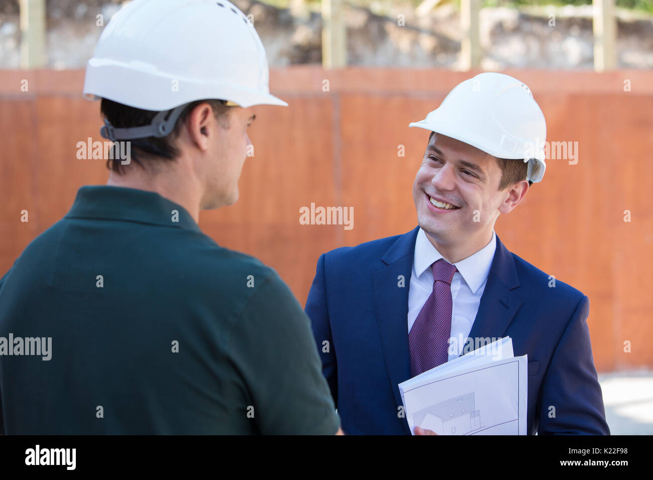 Geschäftsmann Händeschütteln mit Builder auf Baustelle Stockfoto