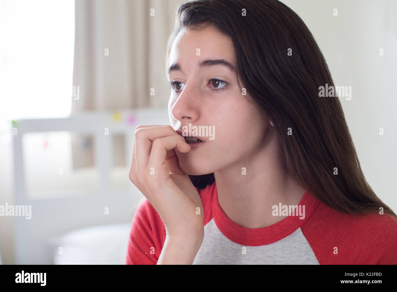 Junges Mädchen sitzen im Schlafzimmer Beißen Nägel Stockfoto