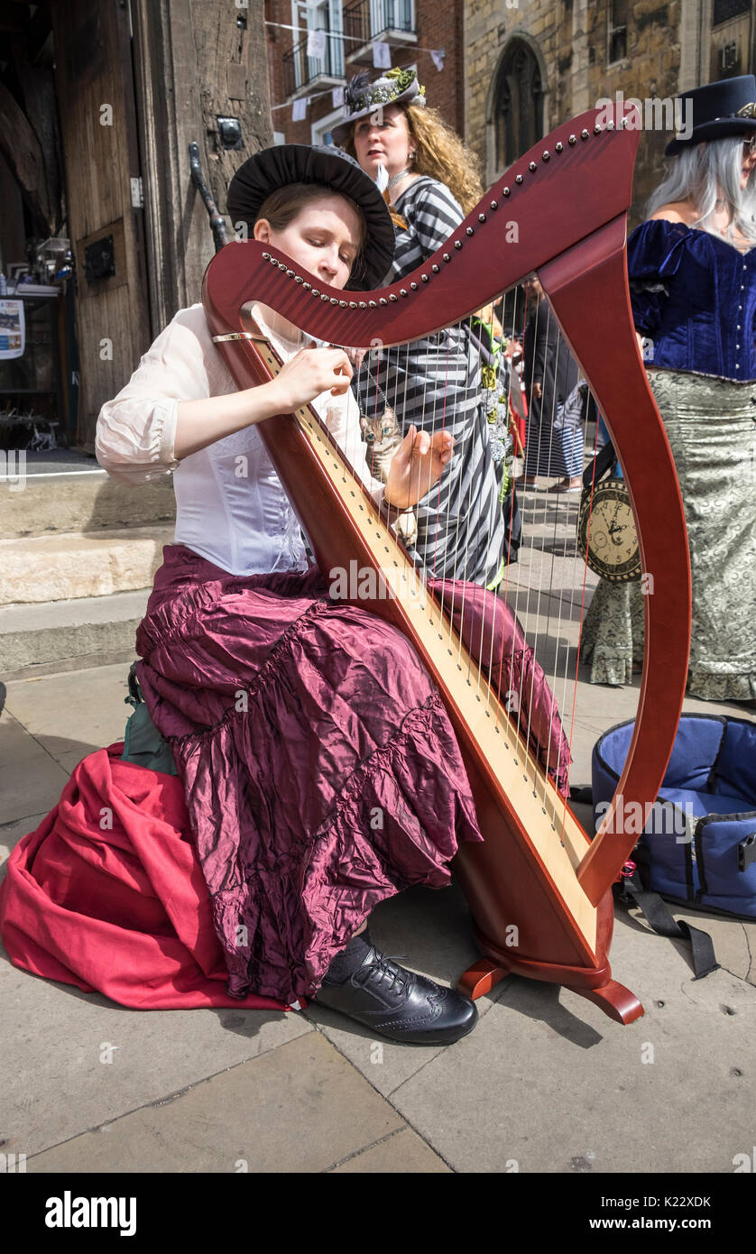 Junge Frau spielt die Harfe in Lincoln, während der 2017 Steampunk Asyl Festival, Stadt Lincoln, Lincolnshire, Großbritannien Stockfoto