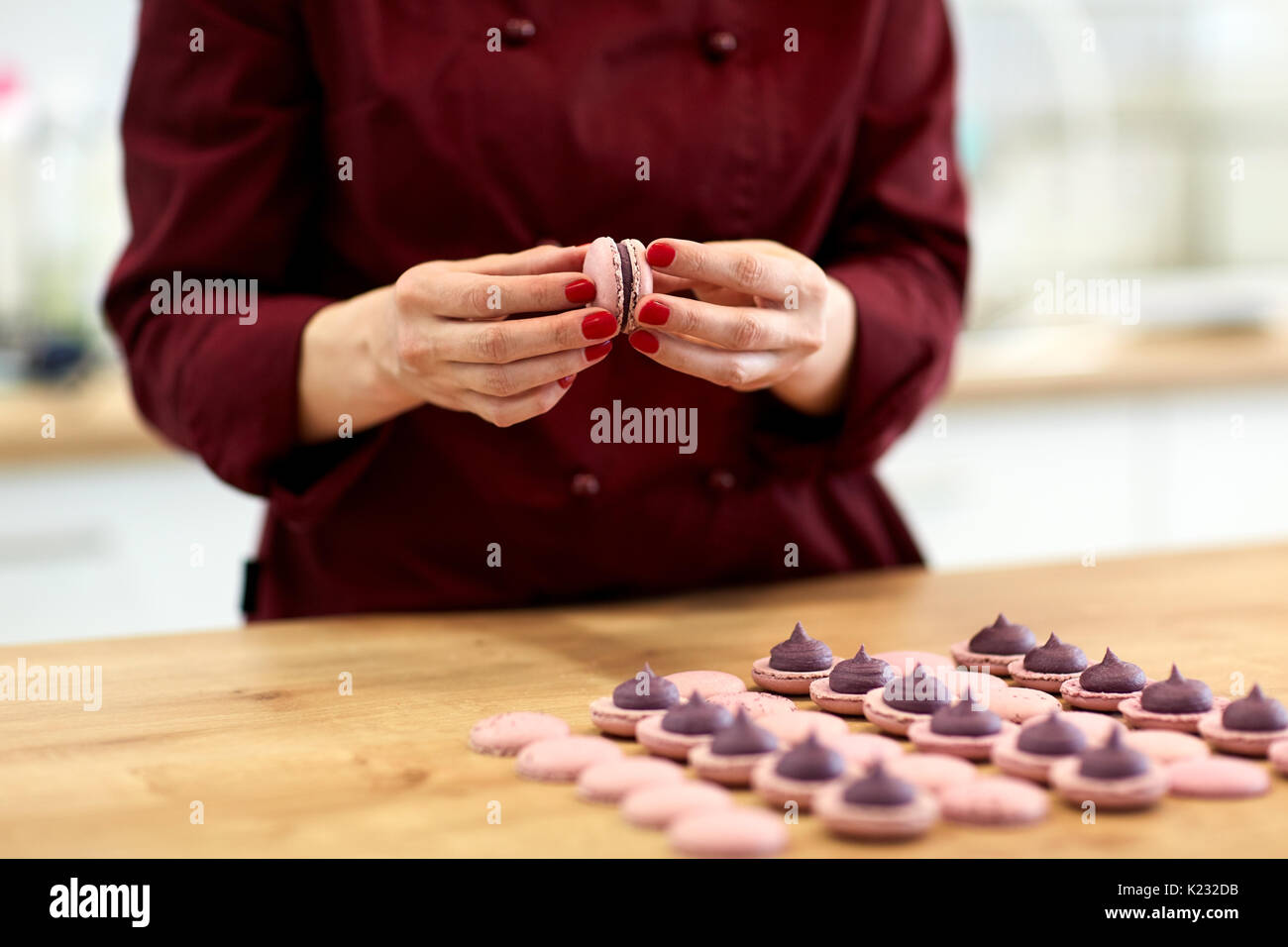 Koch sandwiching macarons Schalen mit Sahne Stockfoto