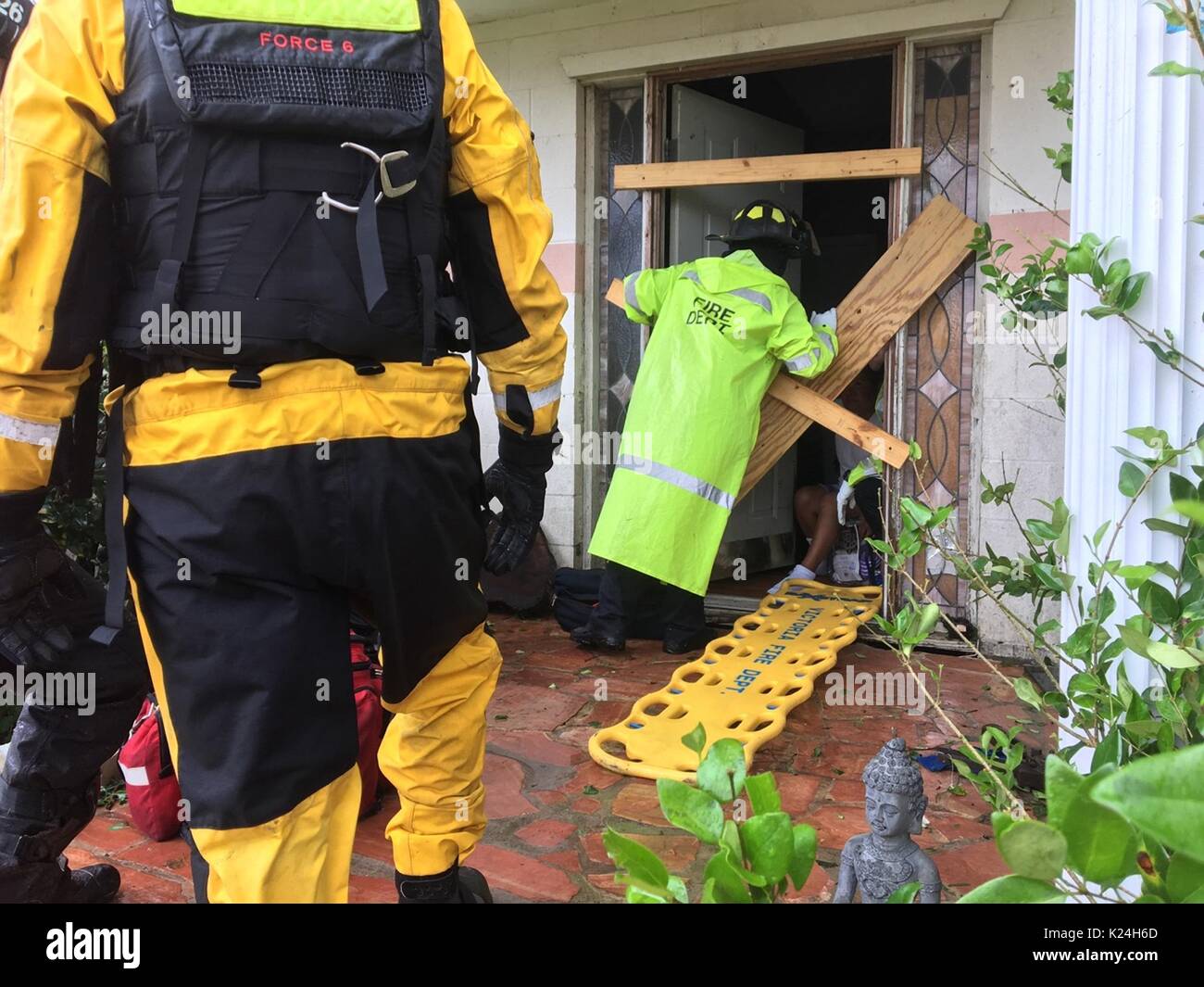 Feuerwehrleute bieten Hilfe für die Bewohner in einem Haus durch den Hurrikan Harvey 27. August 2016 in Victoria, Texas beschädigt. Stockfoto