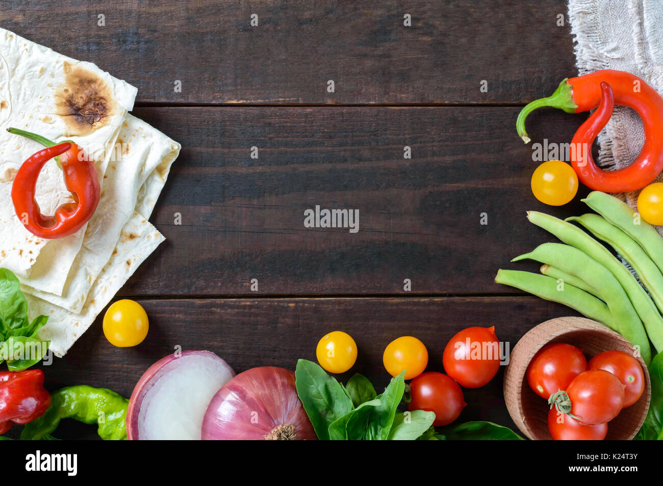 Essen Hintergrund: Cherry Tomaten, Chili, Basilikum, Grüne Bohnen, Zwiebeln, pita Brot auf einem dunklen Holz- Board. Stockfoto