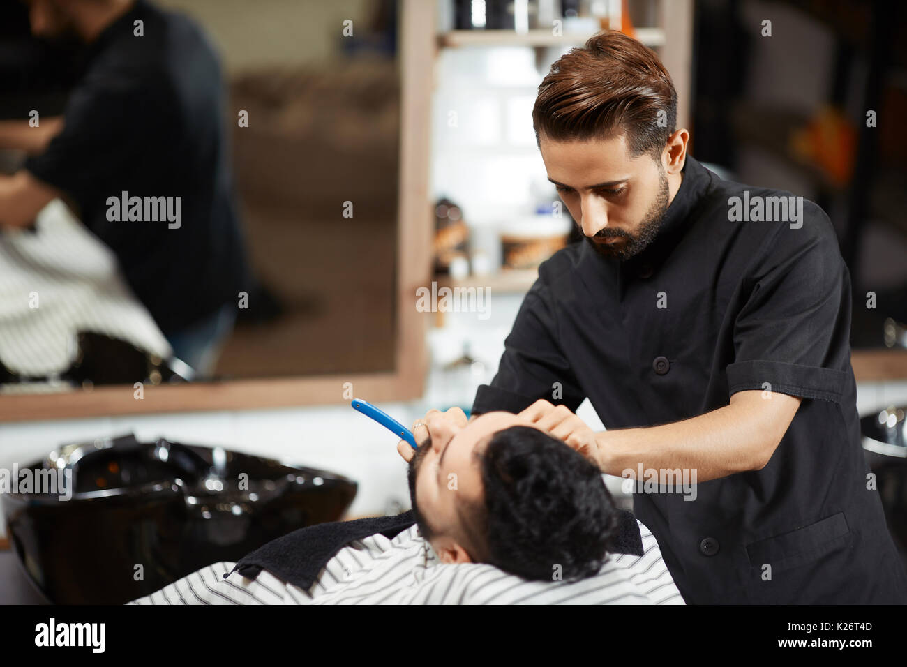 Hairstylist in Schwarz suite Rasieren und Schneiden Brot des Client. Stockfoto