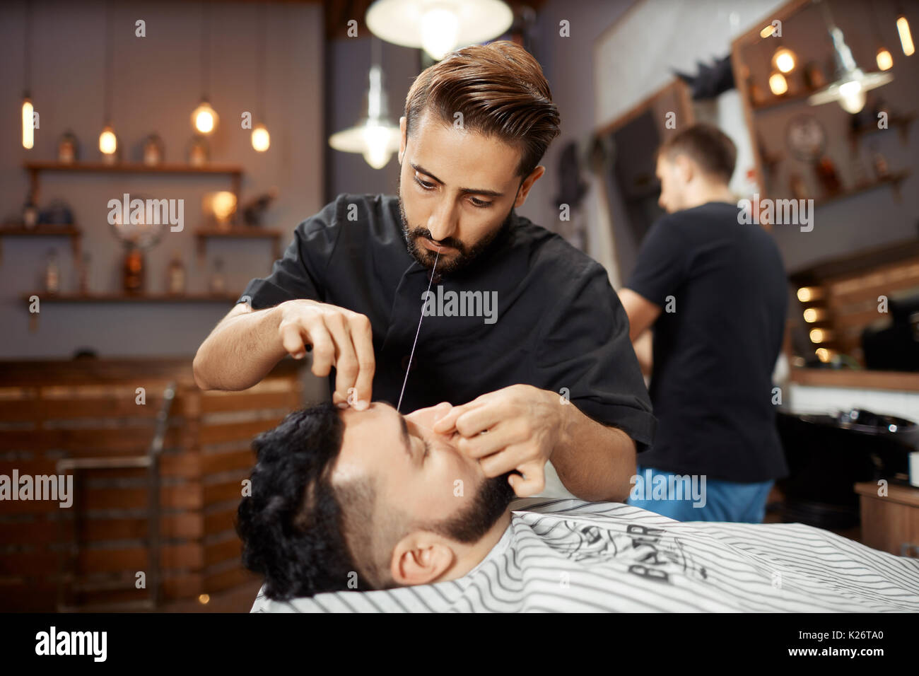 Friseur arbeiten bei Barbershop, die Korrektur von Brot mit weißem Faden. Stockfoto