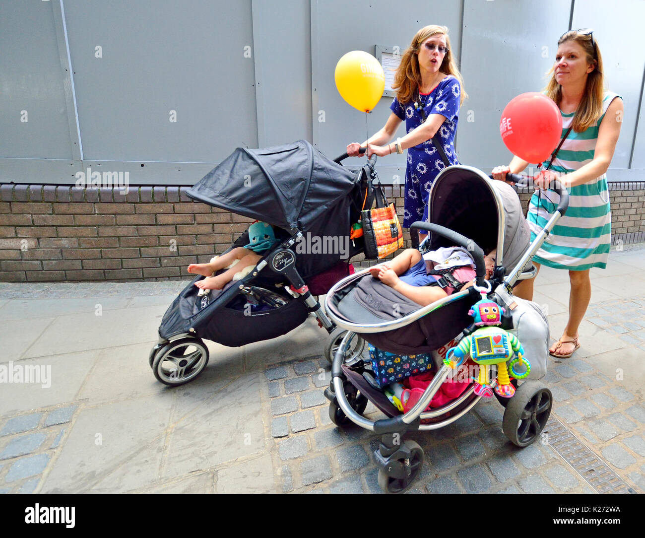London, England, UK. Zwei junge Mütter mit Kindern in Kinderwagen und Ballons Stockfoto