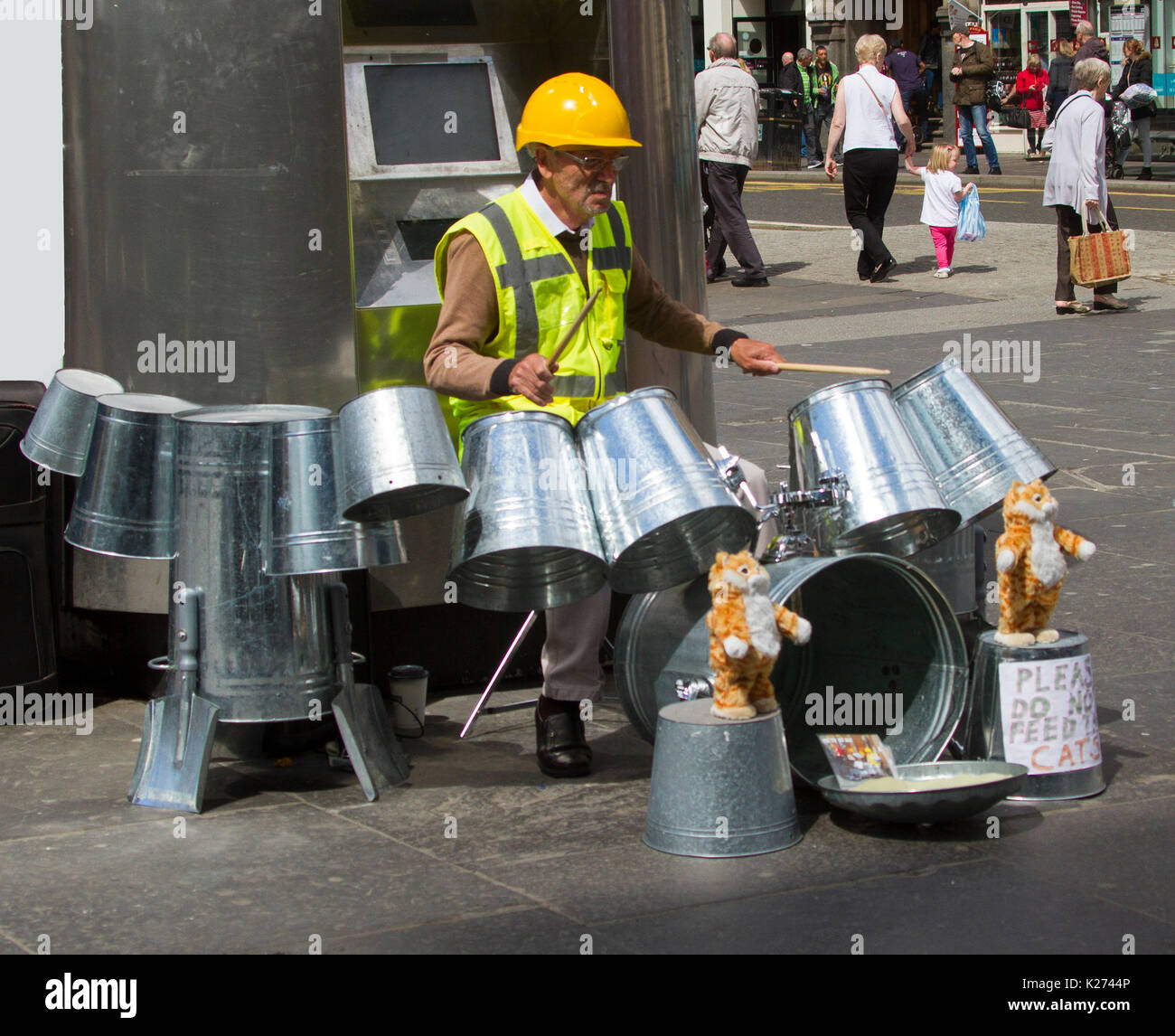 Gaukler, die Techno Zinn Bin Mann, tragen, hart, Hut & hohe Sichtbarkeit Jacke und Wiedergabe von Musik auf Metall Mülleimer in der Stadt Glasgow, Schottland Stockfoto