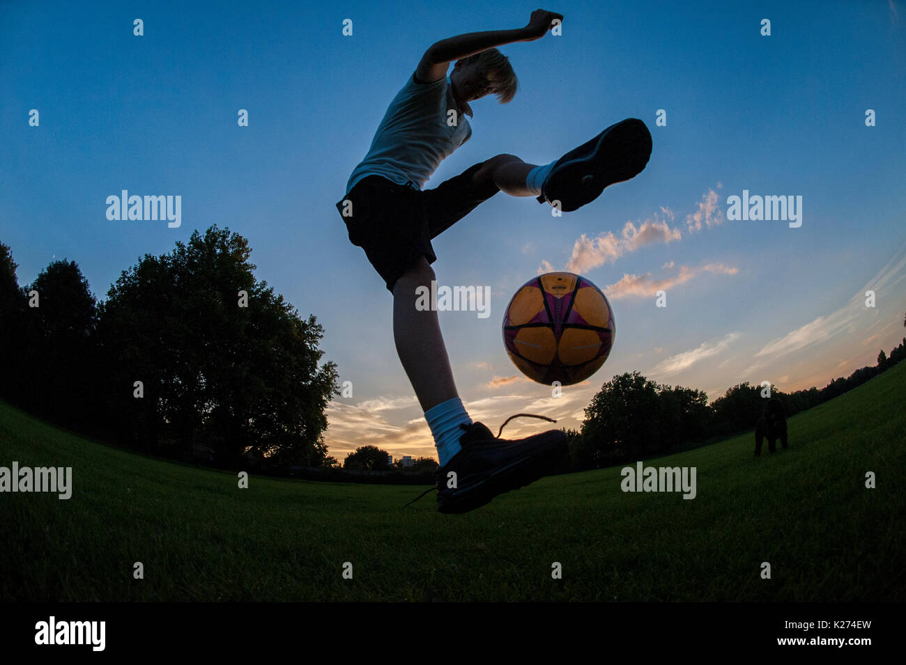 Ein Junge Fußball spielen und üben seine fußballerischen Fähigkeiten und Tricks in einem Londoner Park Stockfoto