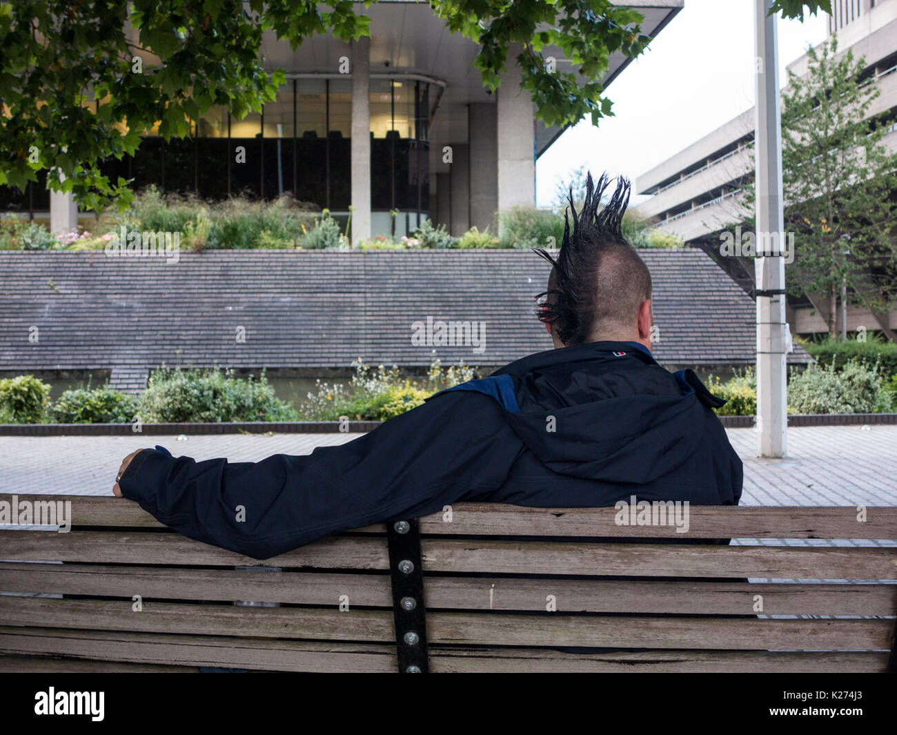 Ein Mann mit einem mohican Haarschnitt entspannen auf einer Werkbank Stockfoto