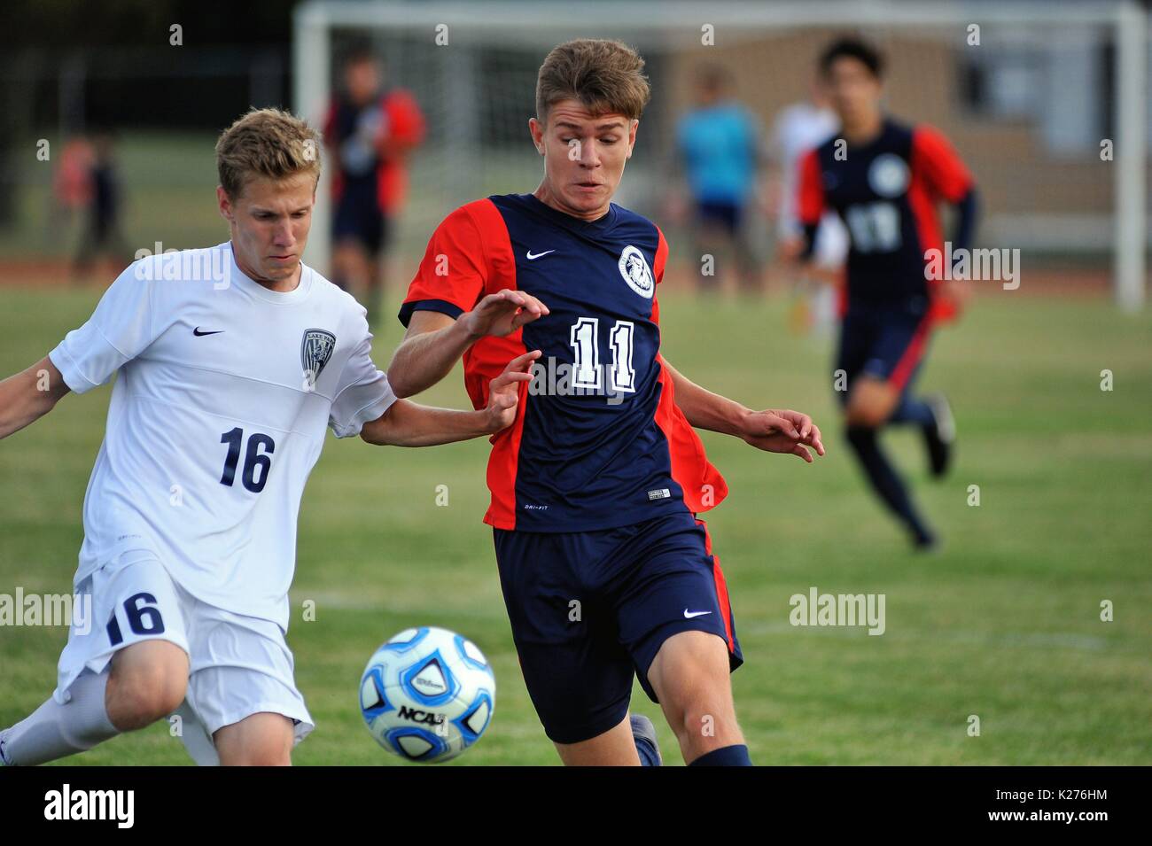 Gegnerische Spieler, die Schritt für Schritt im Streben nach einem hohen Ball während eines High School übereinstimmen. USA. Stockfoto