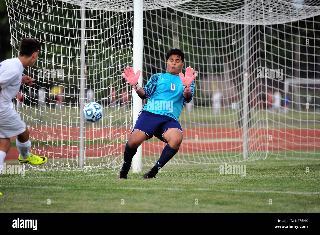 Keeper beginnt eine tauchen Sie Winkel auf einer kurzen Strecke Schuß während ein High School Spiel zu schneiden. Stockfoto