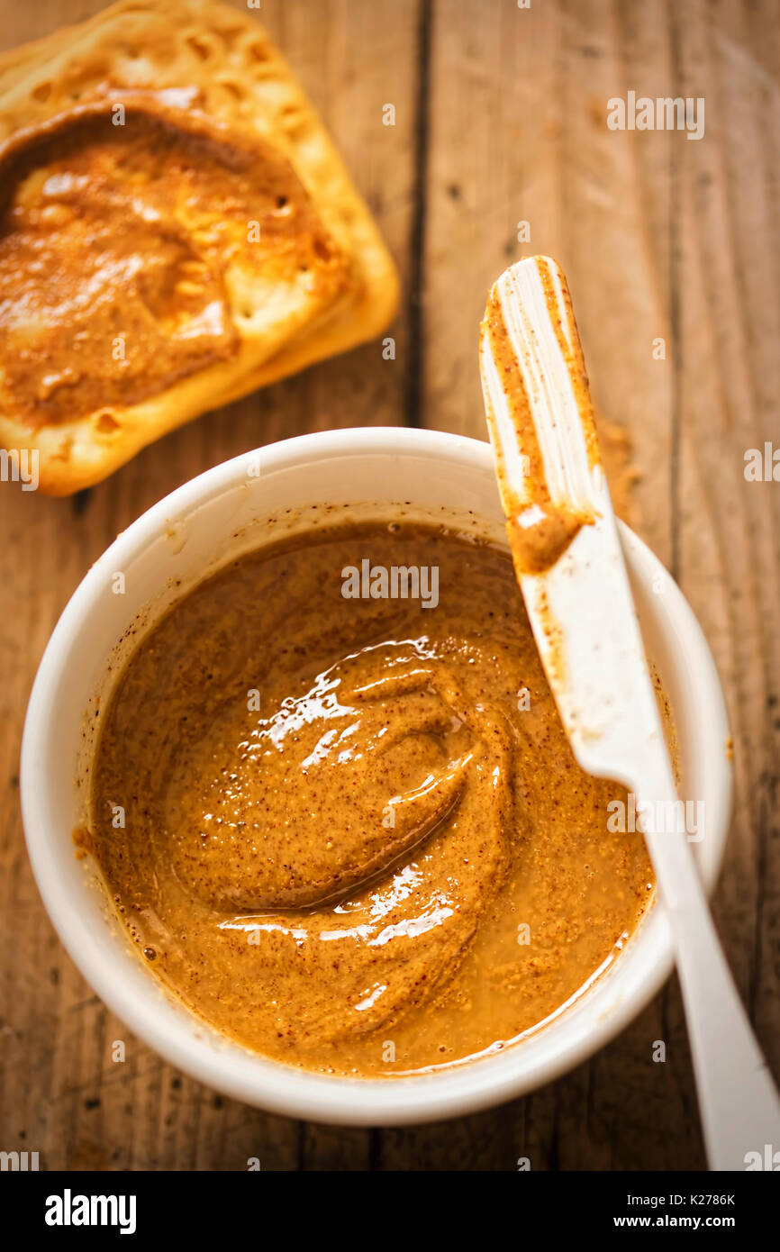 Almond Butter in Schüssel mit Crackern auf hölzernen Tisch Stockfoto