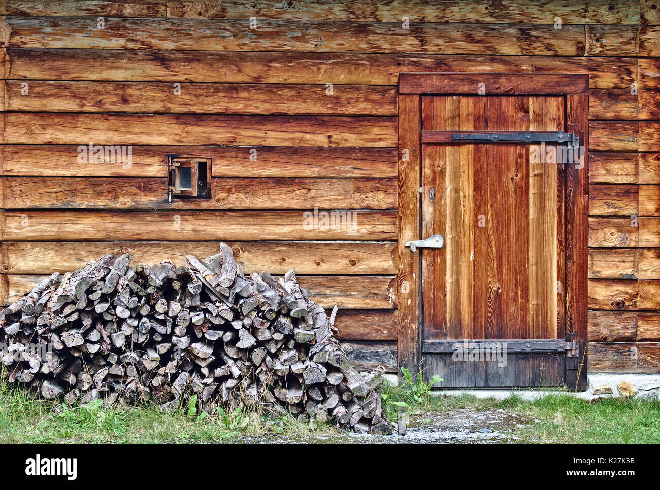 Blockhaus Wand mit kleinen Fenster-, Tür- und kleinen Holz Stapel Stockfoto