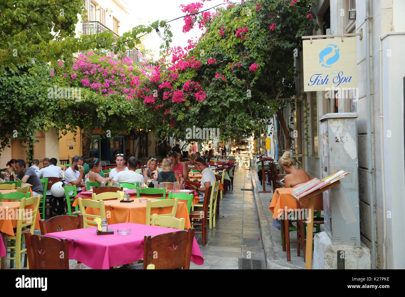 Farbenfrohe Restaurant im freien Tische in einer Gasse in Ermoupoli, Syros, Griechenland, im Schatten von Reben und Blumen. Stockfoto