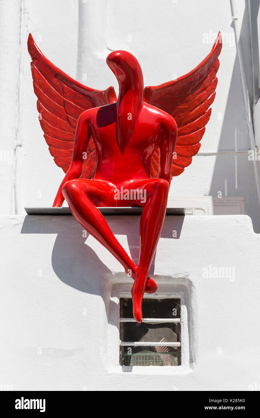 Eine rote abstrakte Engel Skulptur an der Wand, Mykonos, Griechenland sitzen. Stockfoto