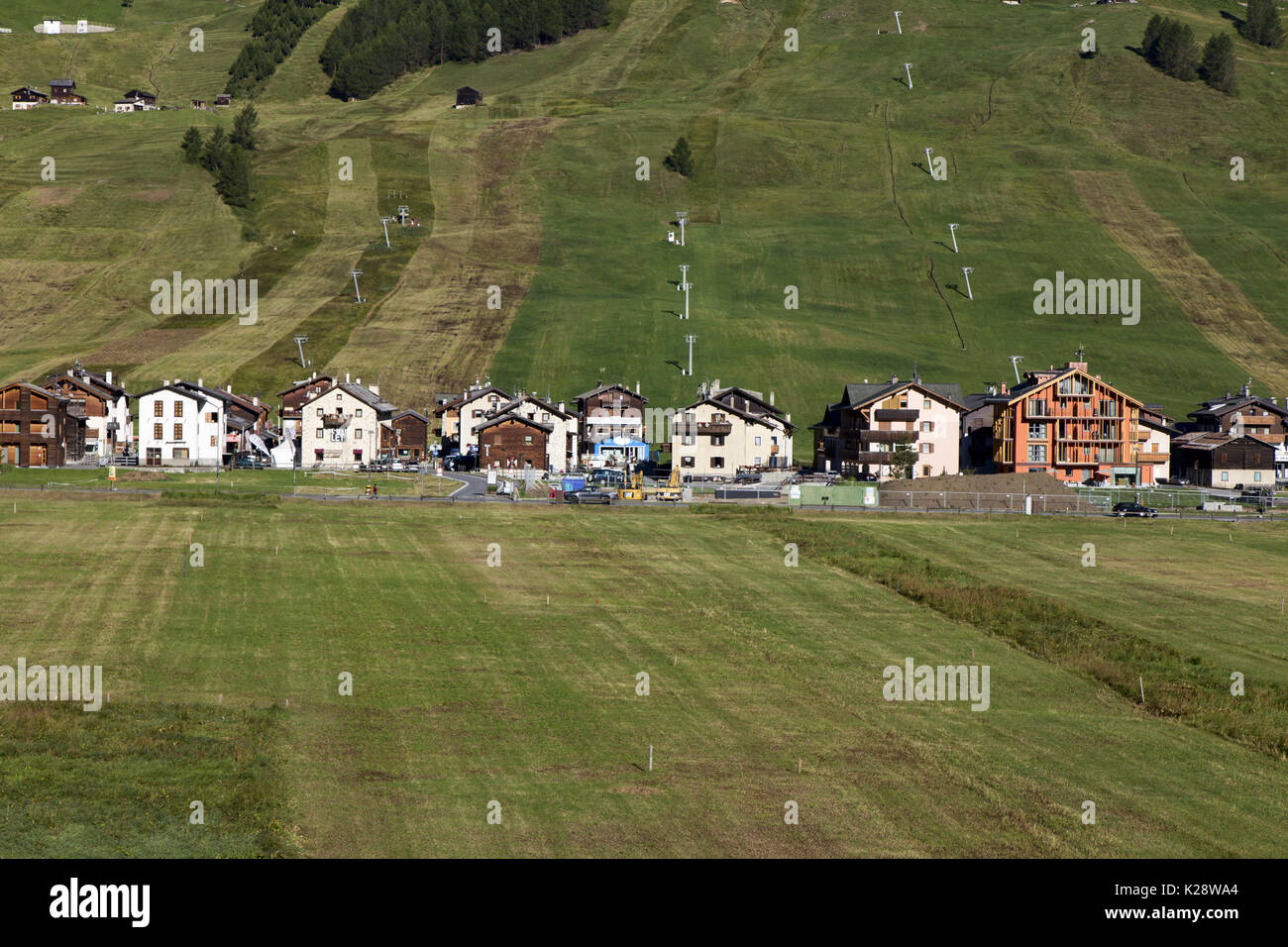 Weite Landschaft, Blick auf die kleine Stadt auf weiten grünen Ebenen mit mehreren Gebäuden und grünes Gras und keine Leute in Sicht Stockfoto