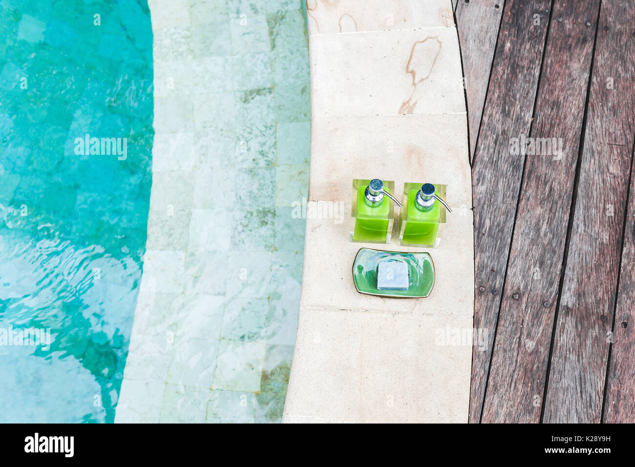 Zwei Flaschen Shampoo und handgemachte Seife am Rande der Pool mit Türkis und transparente sauberes Wasser. Stein und Holz- Hintergrund. Dusche und Spa kit i Stockfoto