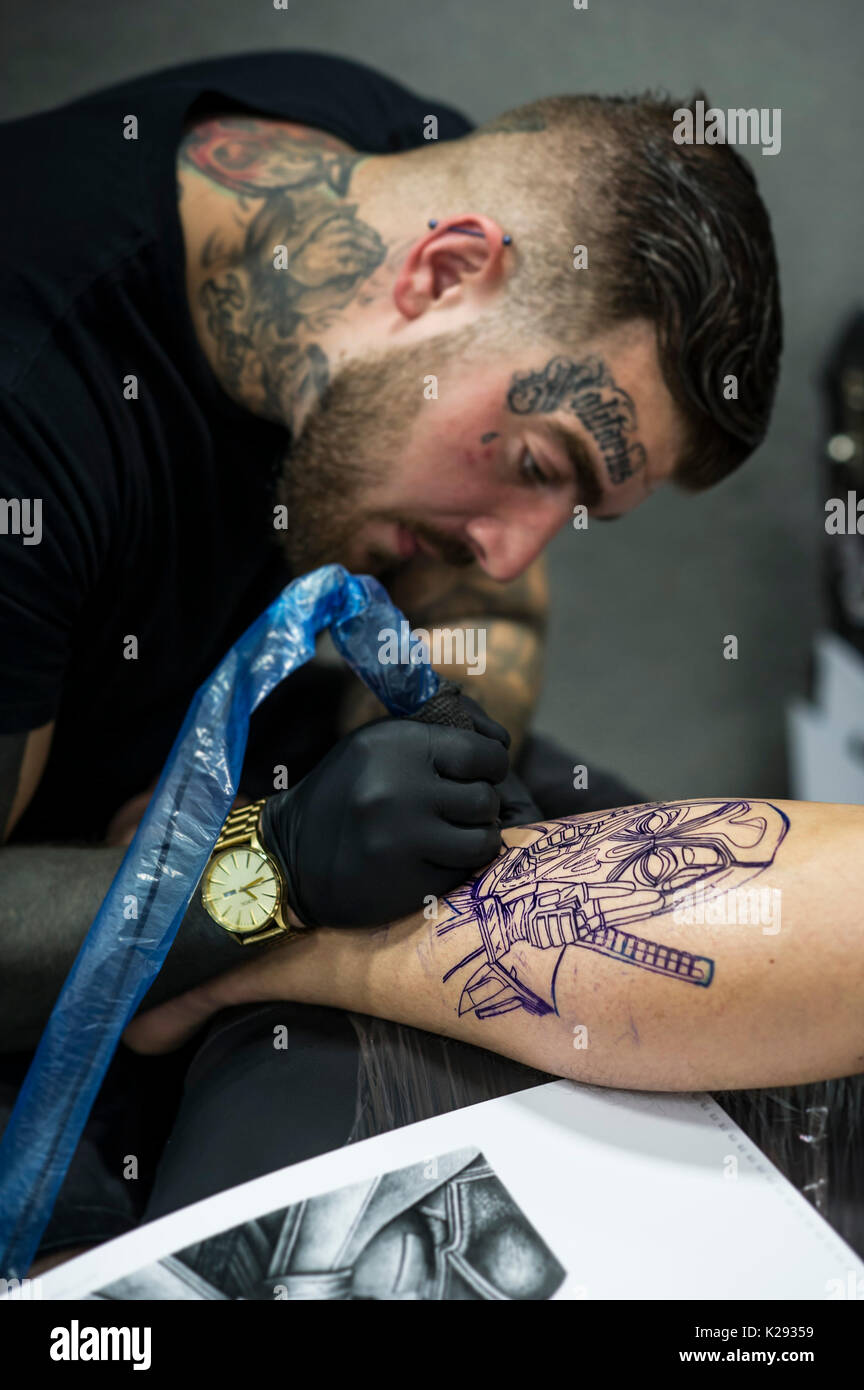 Tätowierungen. Lukas Rudden Tätowieren ein Design auf das Bein eines männlichen Kunden am Cornwall Tattoo Convention. Stockfoto