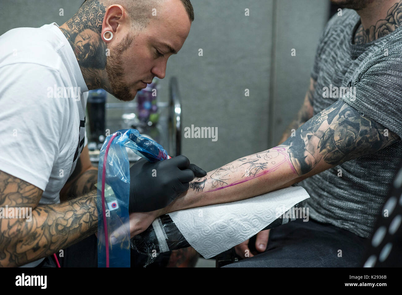 Tätowierungen. Ein Tätowierer arbeiten auf dem Unterarm eines Kunden bei der Cornwall Tattoo Convention. Stockfoto
