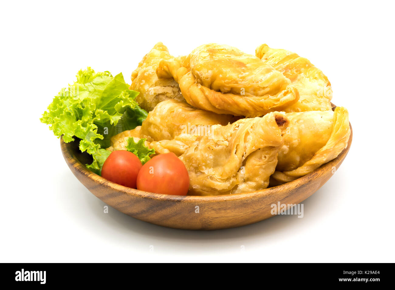 Curry Puffs, Tomaten und Salat in eine hölzerne Schüssel auf weißem Hintergrund Stockfoto