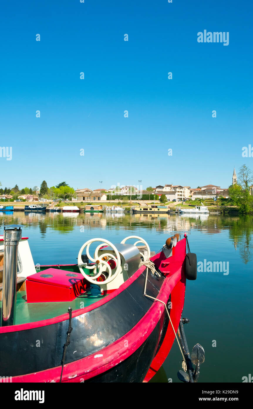 Ein buntes Boot im Frühjahr morgen Sonnenschein vertäut auf dem ruhigen Fluss Lot am Port de Penne (die alten Fluss port für Penne d'Agenais), Lot-et-Garonne, Frankreich. Auf der anderen Seite des Flusses ist Saint-Sylvestre-sur-Lot. Stockfoto