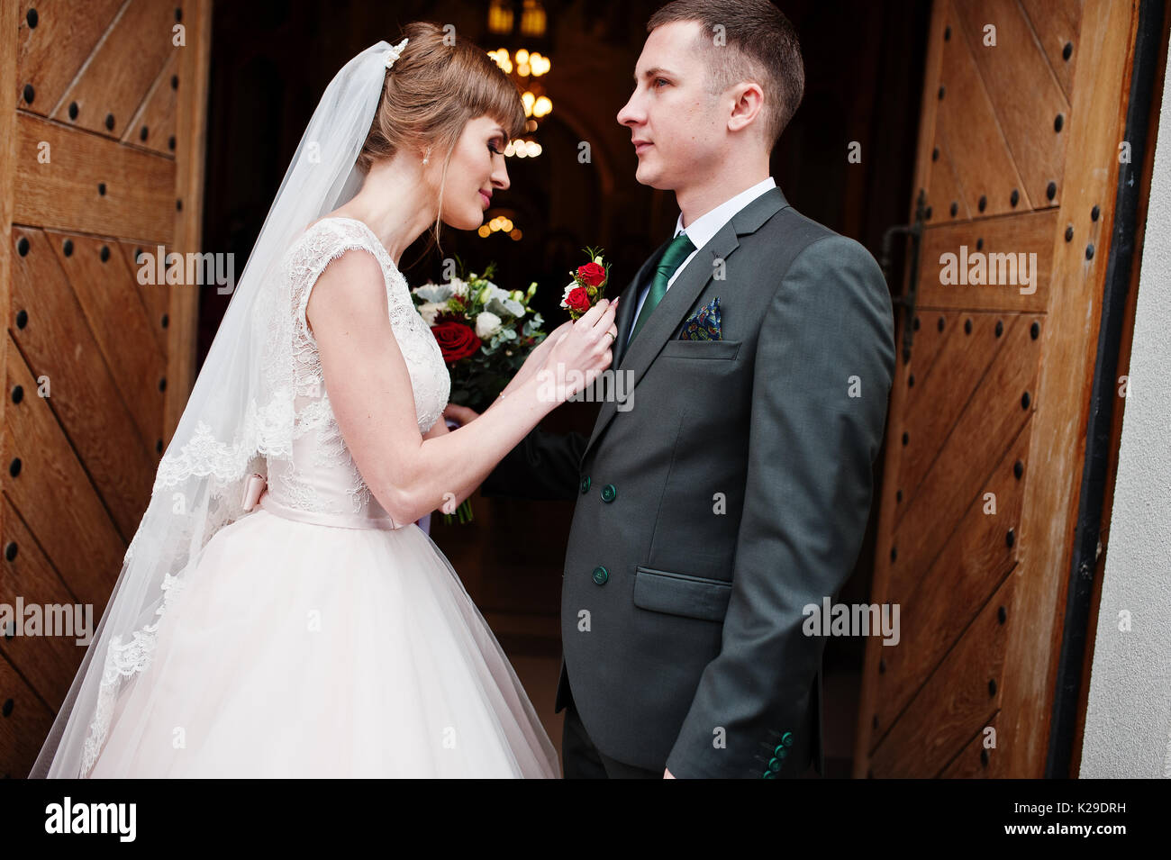 Schöne Braut pinning ein knopfloch Blume bis zu einem Bräutigam Jacke. Stockfoto