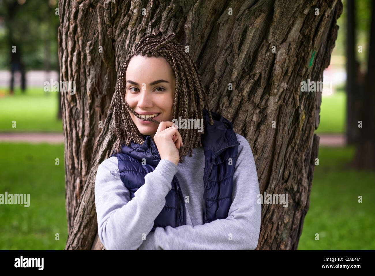 Porträt einer positiven Jugendmädchen mit geflochtenen Zöpfen. Sie lächelt breit und voll Zuversicht blickt Stockfoto