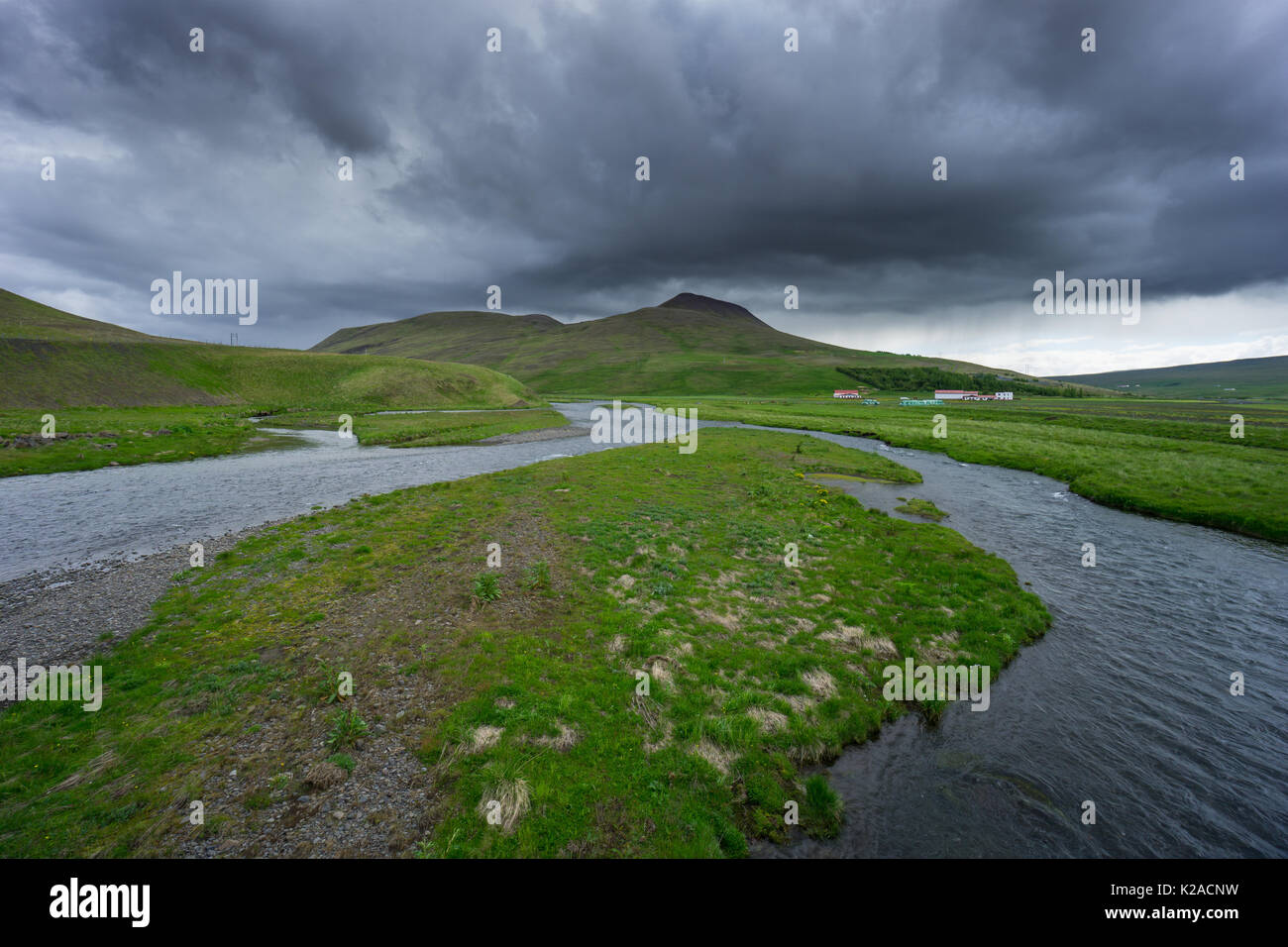 Island - Natürliche Flusslauf durch grüne Felder und unberührte Landschaft Stockfoto