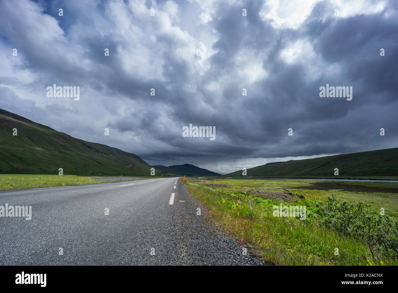 Island - Straße durch grüne Tal und den Fluss mit Regen weit entfernt Stockfoto