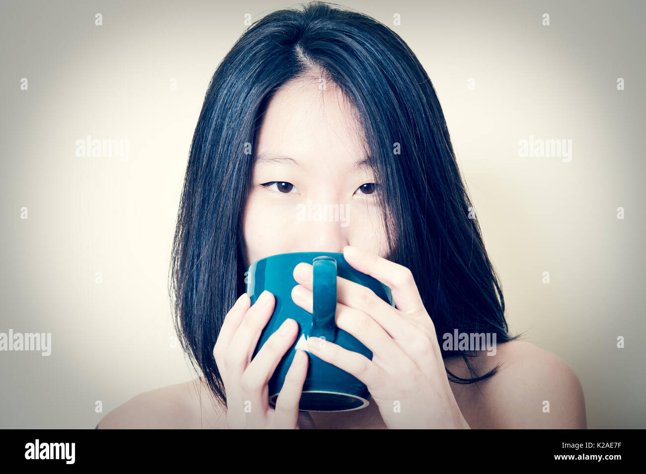 Junge schöne asiatische Frau gerne zur Kamera Portrait mit blauen petroleum Becher auf den Mund, suchen Stockfoto