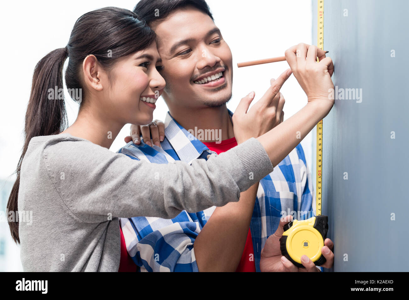 Junge indonesische Paar Messung der Wände in der neuen Wohnung Stockfoto