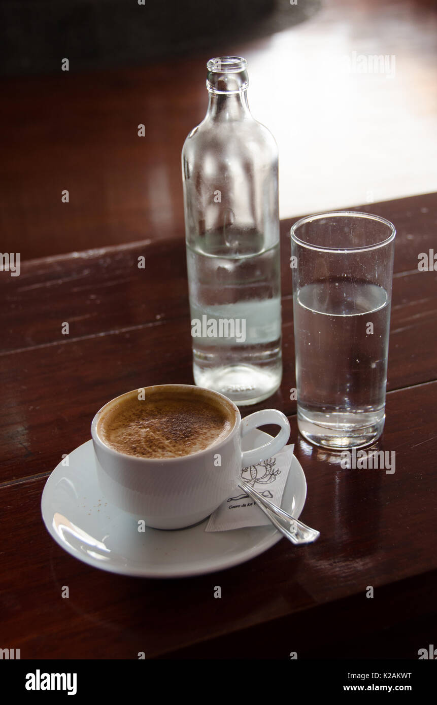 Cappuccino Kaffee und ein Glas Flasche Wasser Stockfoto