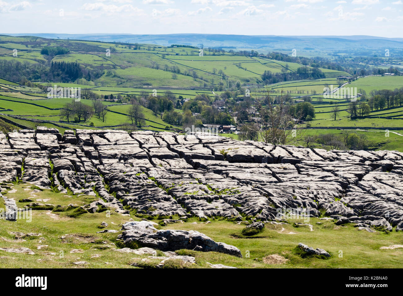 Clints und grikes in Kalkstein Pflaster an der Oberseite des Malham Cove mit Dorf hinaus. Malham Yorkshire Dales National Park England Großbritannien Stockfoto
