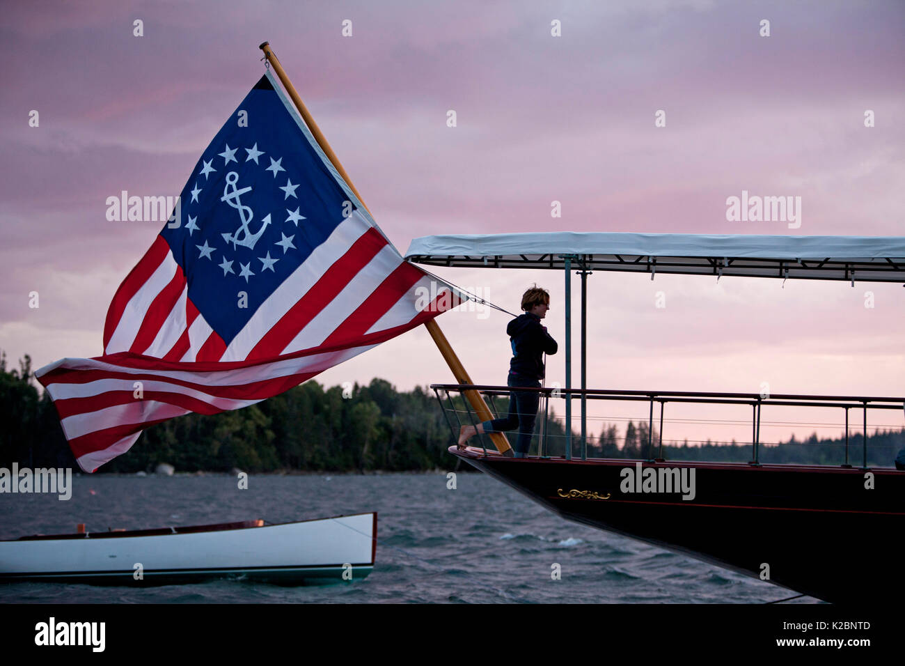 Mann mit Fahne Flagge der Vereinigten Staaten an Bord des Dampfschiffes Cangarda, Maine, USA. August 2010. Stockfoto