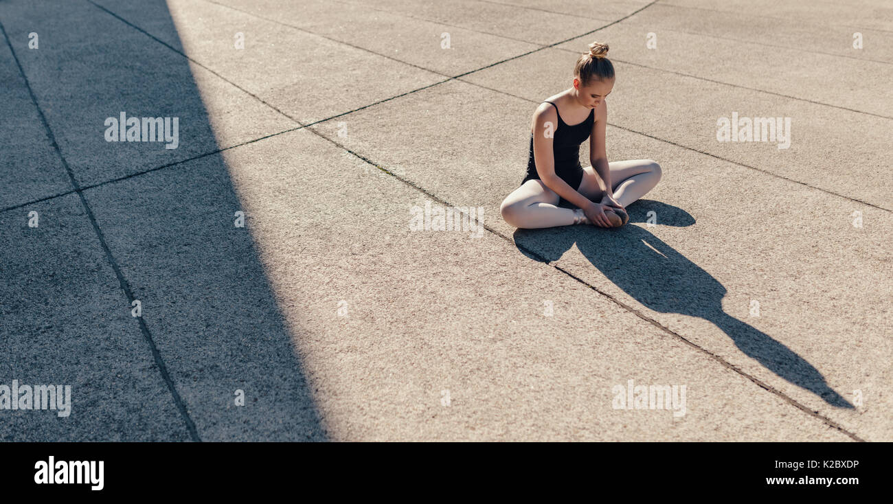 Ballett Tänzerin ihre Beine strecken, bevor Tanz üben. Tänzerin sitzen auf  dem Boden verbinden beide die Füße Stockfotografie - Alamy