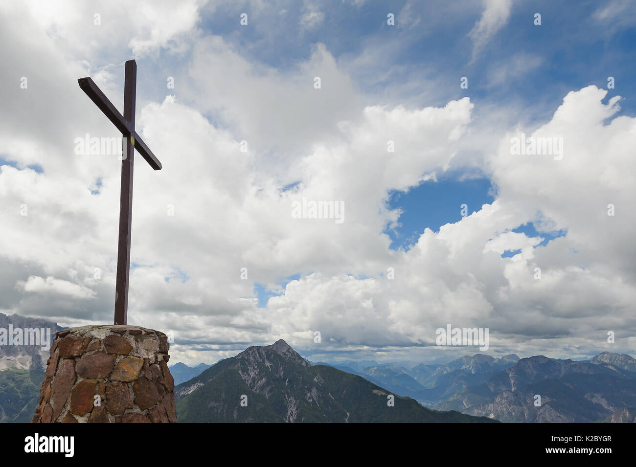 Kreuz aus Holz auf dem Gipfel des Berges. Berglandschaft über den Wolken. Kreuz auf der Spitze eines Berges, wie üblich in den Alpen. Stockfoto