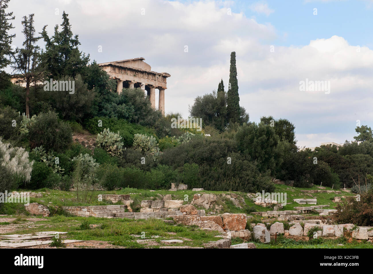 Der Tempel des Hephaistos umgeben von Zypressen (Cupressus sempervirens), Ölbäume (Olea europaea) und Feigenkakteen (Opuntia ficus-indica). Region Attika, Athen, Griechenland, im Januar 2011. Stockfoto