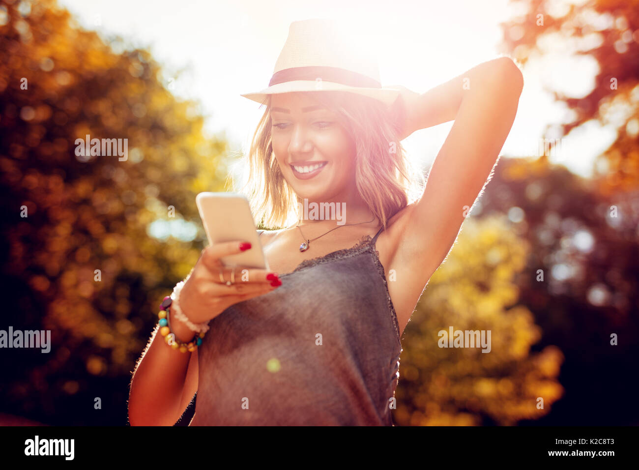 Schönen lächelnden jungen Frau mit Hut Sommer Genießen in der Natur im Herbst und Sie ihr Smartphone. Stockfoto