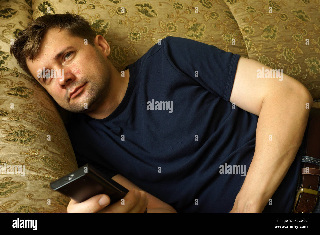 Faul Mann auf einem Sofa vor dem Fernseher. Faulheit Konzept. Stockfoto