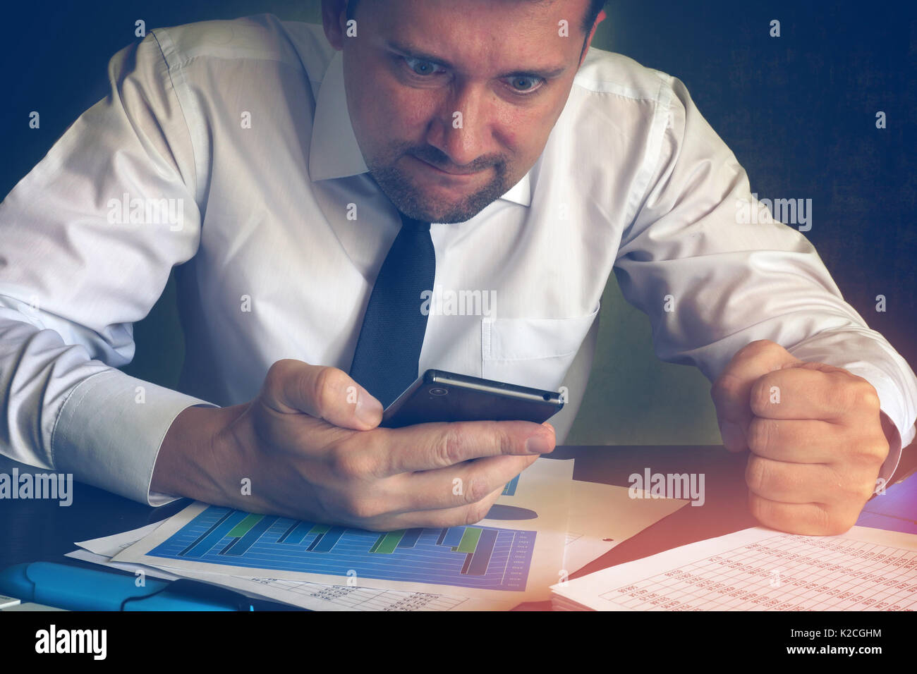 Wütend Geschäftsmann lesen Nachricht in ein Smartphone. Probleme in einem Unternehmen. Stockfoto