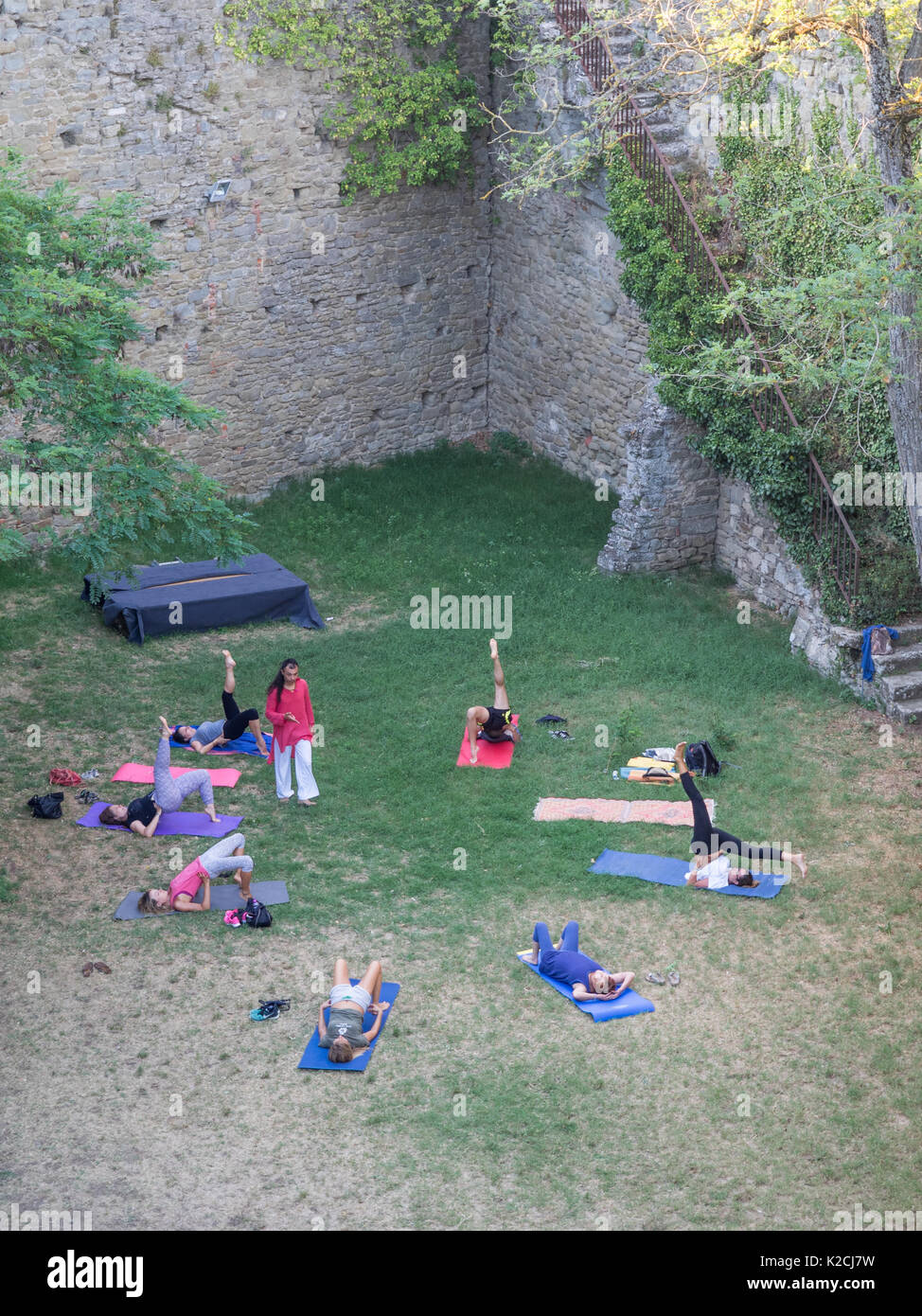 Yogi Yoga Übung Lehrer unterrichten, eine Klasse in einem Kreis außerhalb im Freien im Garten Rasen im Schatten von Sonne und Hitze Stockfoto