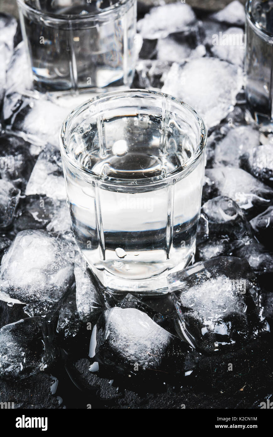 Alkohol und Cocktails. Drei Gläser Wodka auf einer Schiefertafel Fach, mit Eis. Auf einem schwarzen Steintisch. Stockfoto