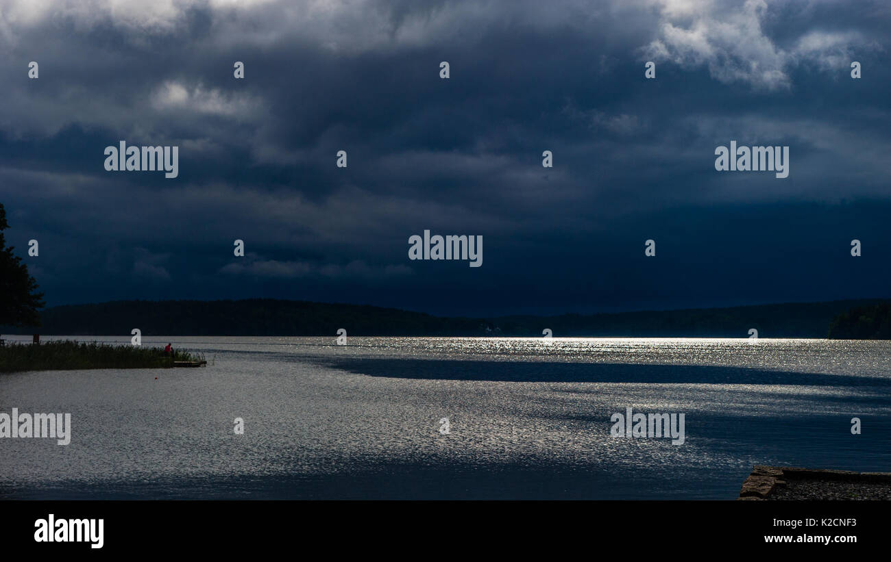 Vor dem Gewitter über der See Malaren, wenn die Sonne noch glitzernde im Wasser und die dunklen Wolken türmen sich über die Skyline Stockfoto