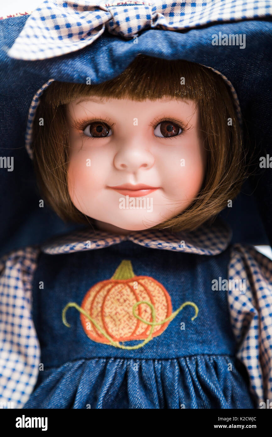 Portrait von Keramik Porzellan handmade vintage Lächeln positive brunette  Puppe in alten Blue Denim Kleid mit orange Kürbis Stickerei, einen großen  Hut, Bug, pl Stockfotografie - Alamy