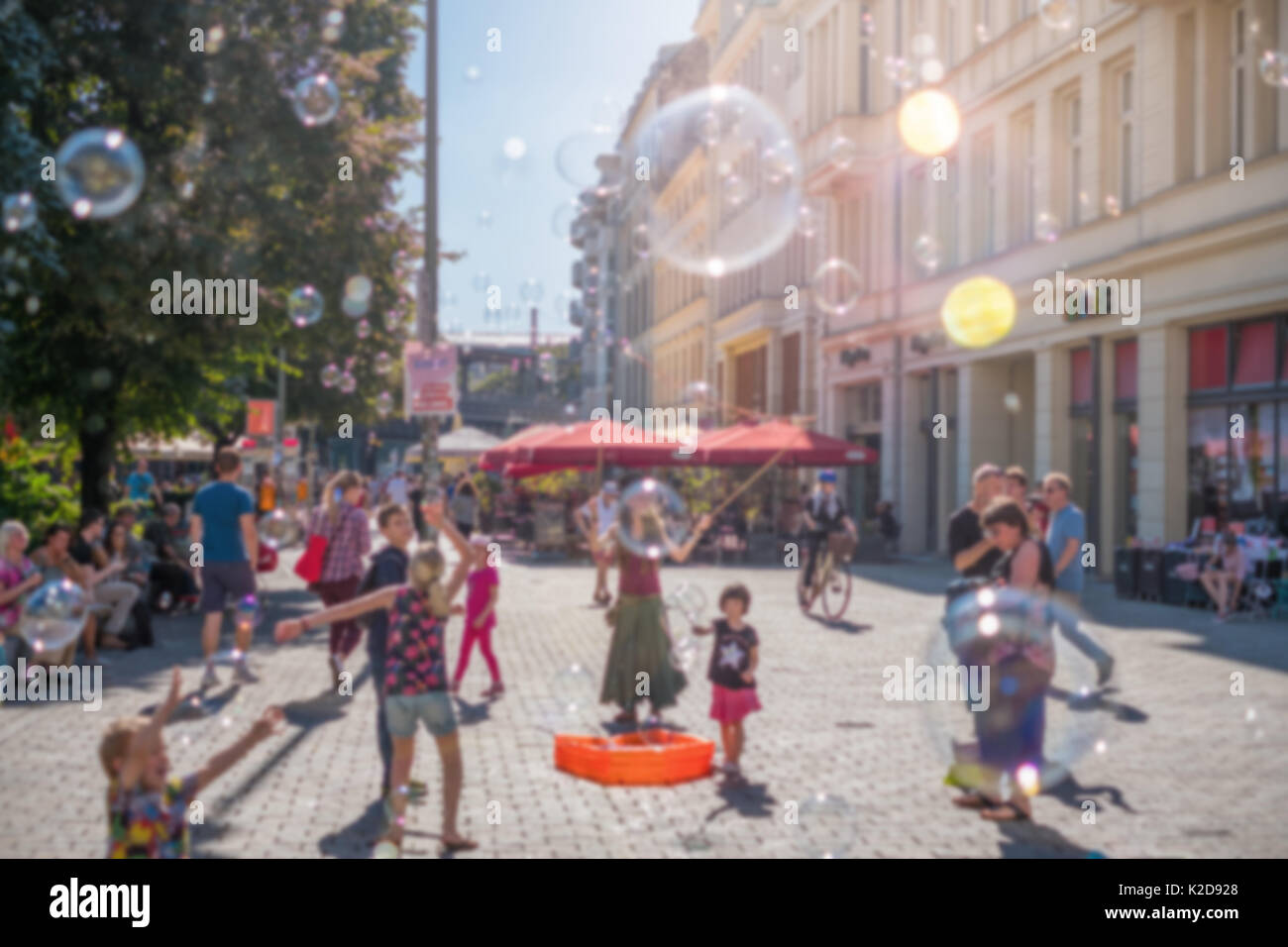 Blurry street scene Konzept - Mädchen machen Seifenblasen an einem sonnigen Tag Stockfoto