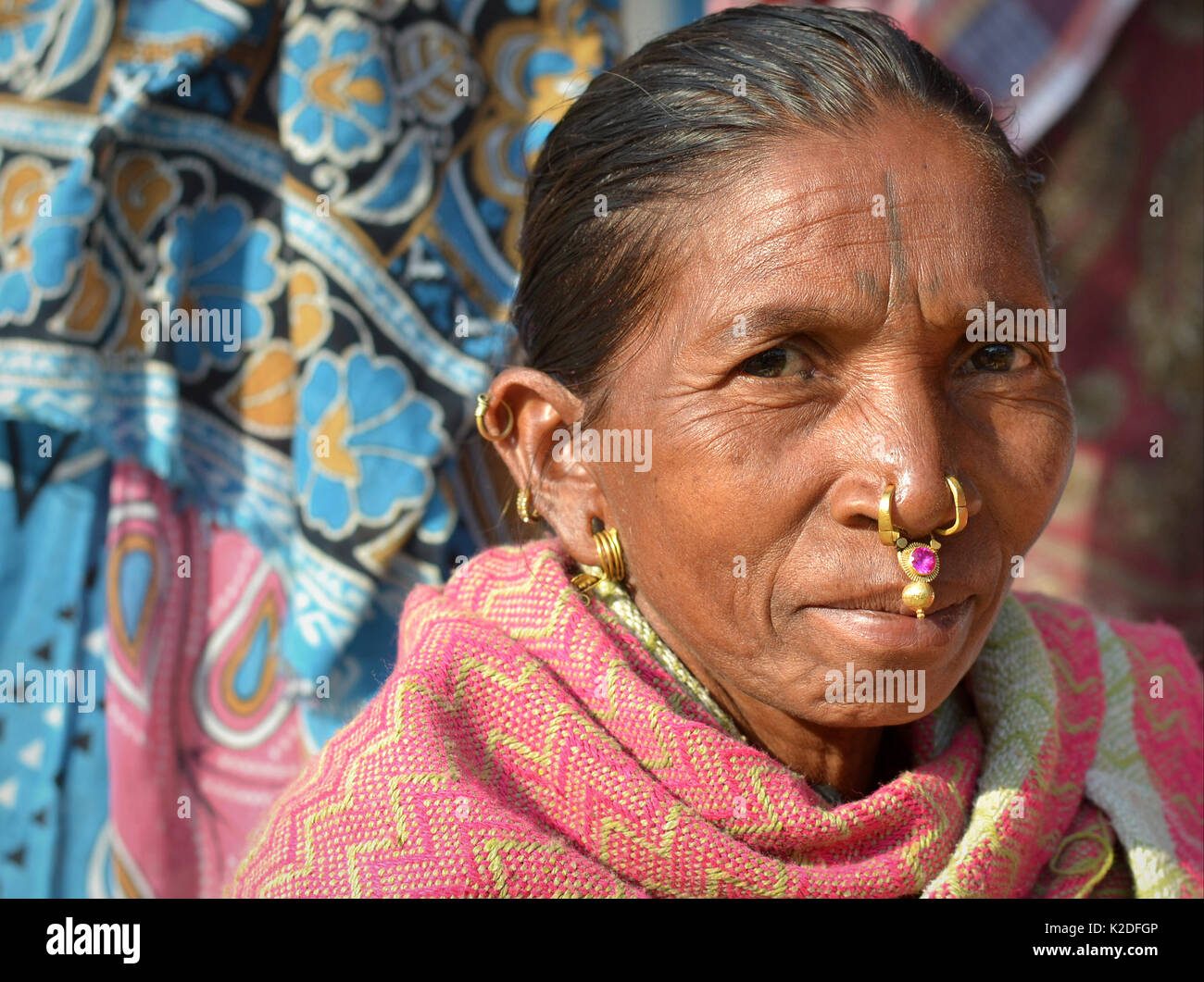 Indische Adivasi-Frau (Stamm der Desia Kondh, Stamm der Kuvi Kondh) mit Gold-und-gemsteinernem Stammesnasenschmuck und goldenem Ohrring lächelt für die Kamera. Stockfoto