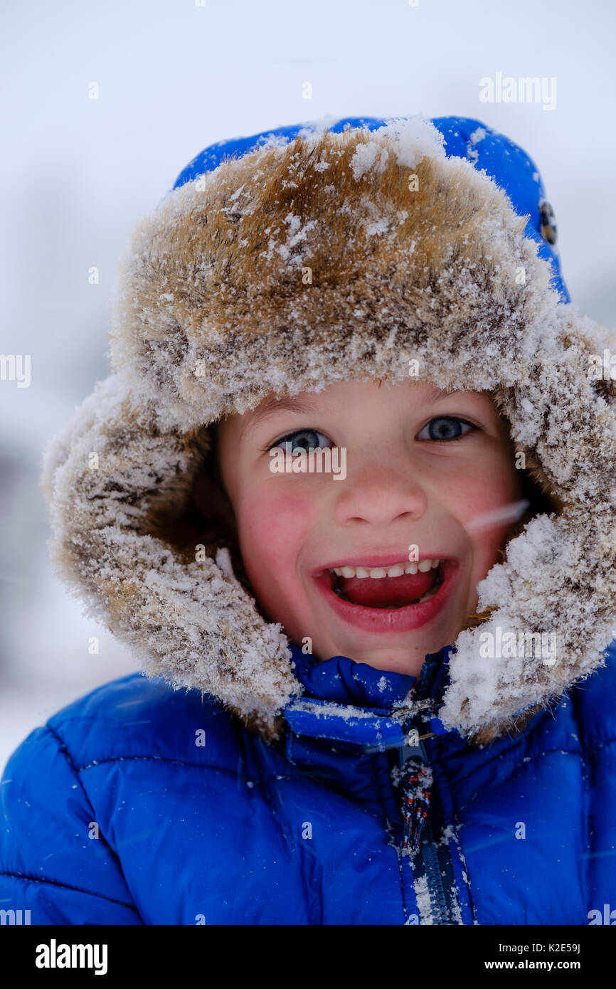 Lachendes Kind, Portrait mit Pelzmütze im Schnee, Deutschland Stockfoto