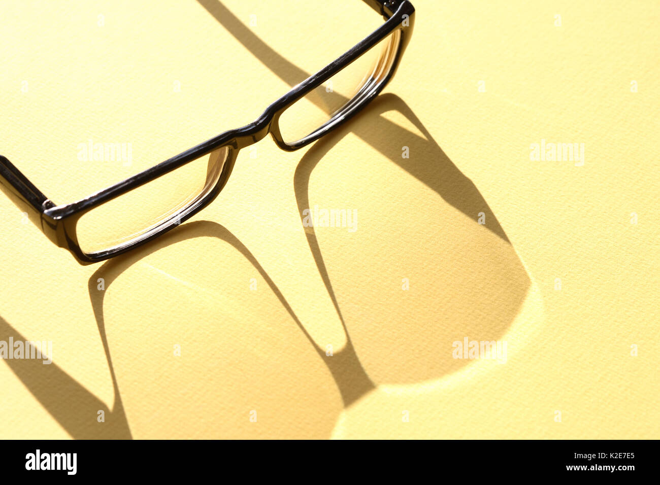 Closeup Brille mit langen Schatten auf gelbe Oberfläche Stockfoto