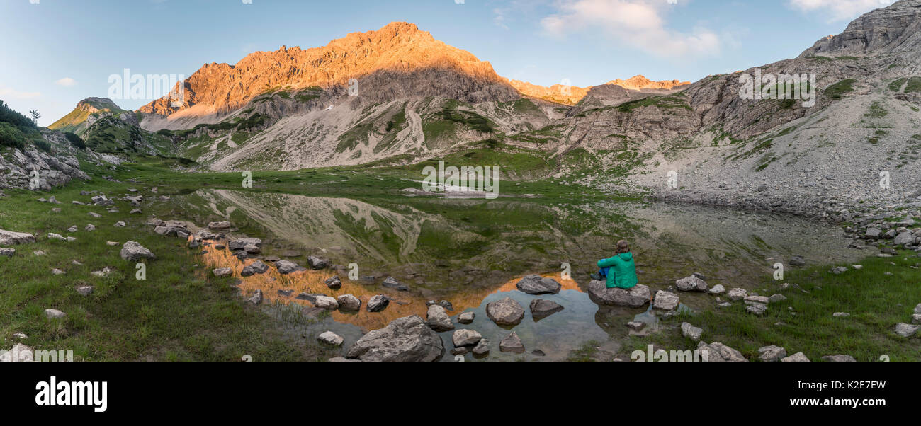 Wandern Frau sitzt auf Felsen, Berge im Abendlicht, Glasfelderkopf links, mitte Fuchskarspitze, Reflexion im Berg Stockfoto